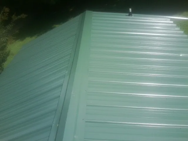 New green metal panels meeting at the ridge of a roof — Flat Roof Repair work by our crew in Middleburg