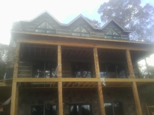 Dormers and porch framing on a large log home under construction — Roof Coating work by our crew in Middleburg